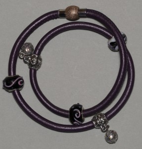 Armbånd med 3 glaskugler og 2 charms på lilla ledersnør med magnetlås.